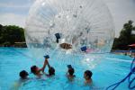 mehrere Kinder spielen mit einem Zorb-Ball im Schwimmerbecken