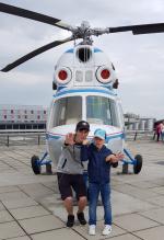 Zwei Jungs posieren vor einem Hubschrauber des Flughafen