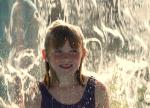 ein kleines Mädchen geniesst eine Dusche unter einem der Wasserpilze
