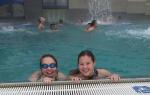 Zwei Mädels beim Schwimmen am Beckenrand, mit einem breiten Grinsen im Gesicht