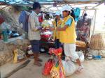 zwei Damen in gelben Westen verteilen Lebensmittel an einen Bedürftigen